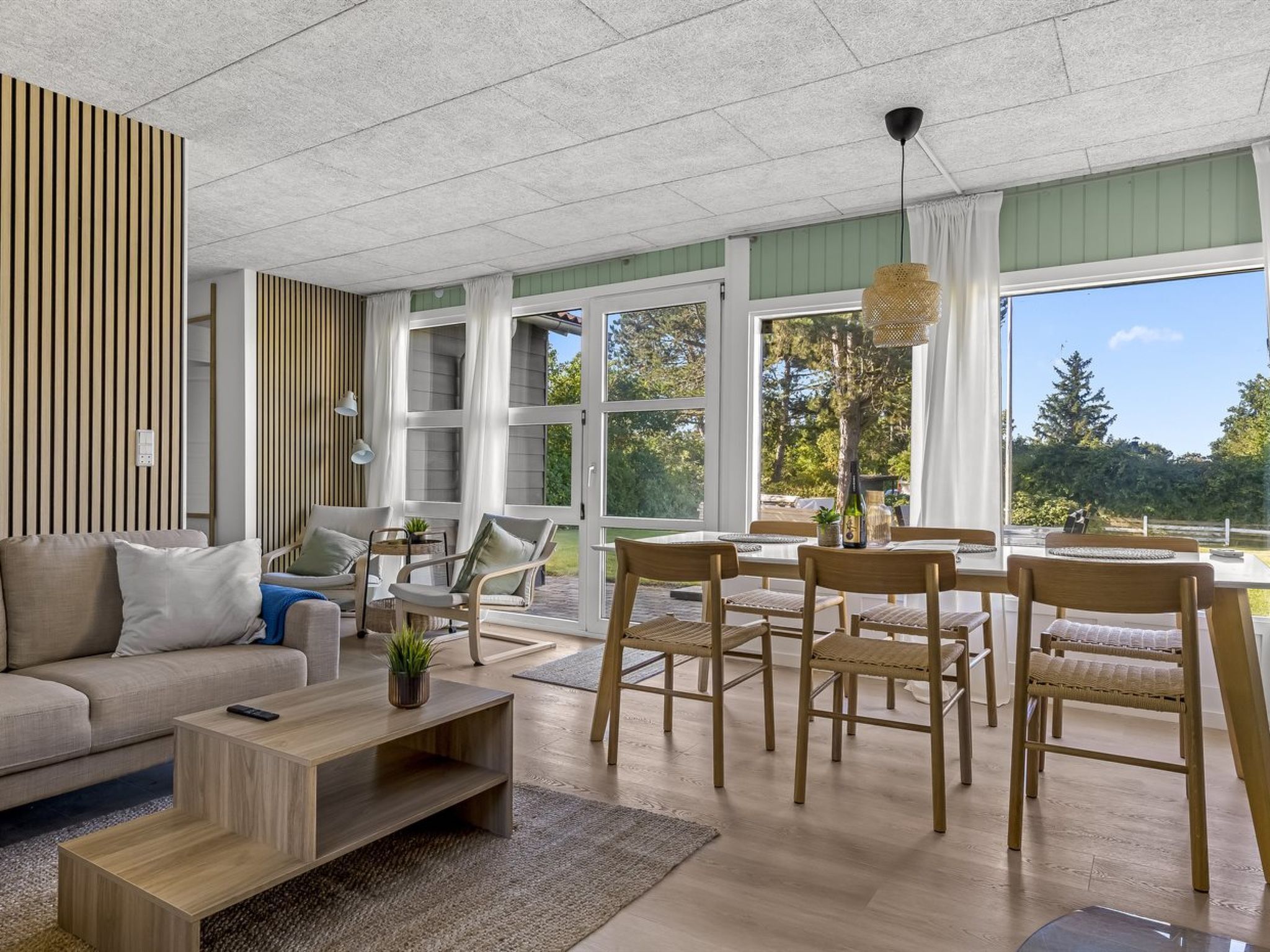A modern living room with a sofa, chairs, a coffee table, and a dining area with a table and chairs.