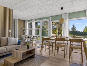 Ein modernes Wohnzimmer mit Sofa, Sesseln, einem Couchtisch und einem Essbereich mit Tisch und Stühlen.