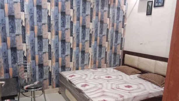 A bedroom with a bed, a chair, and a wall with a patterned design.