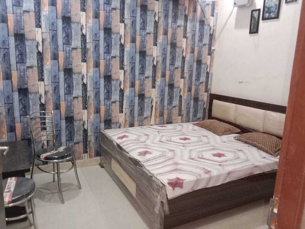 Une chambre à coucher avec un lit, une chaise et un mur orné d’un motif décoratif.