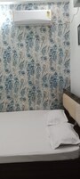 Una habitación con una cama, aire acondicionado de pared y papel tapiz estampado.
