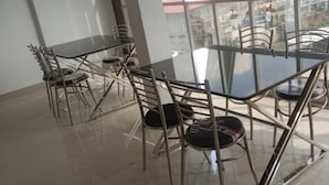 A conference room with a glass table and metal chairs, large windows with a view of the street.