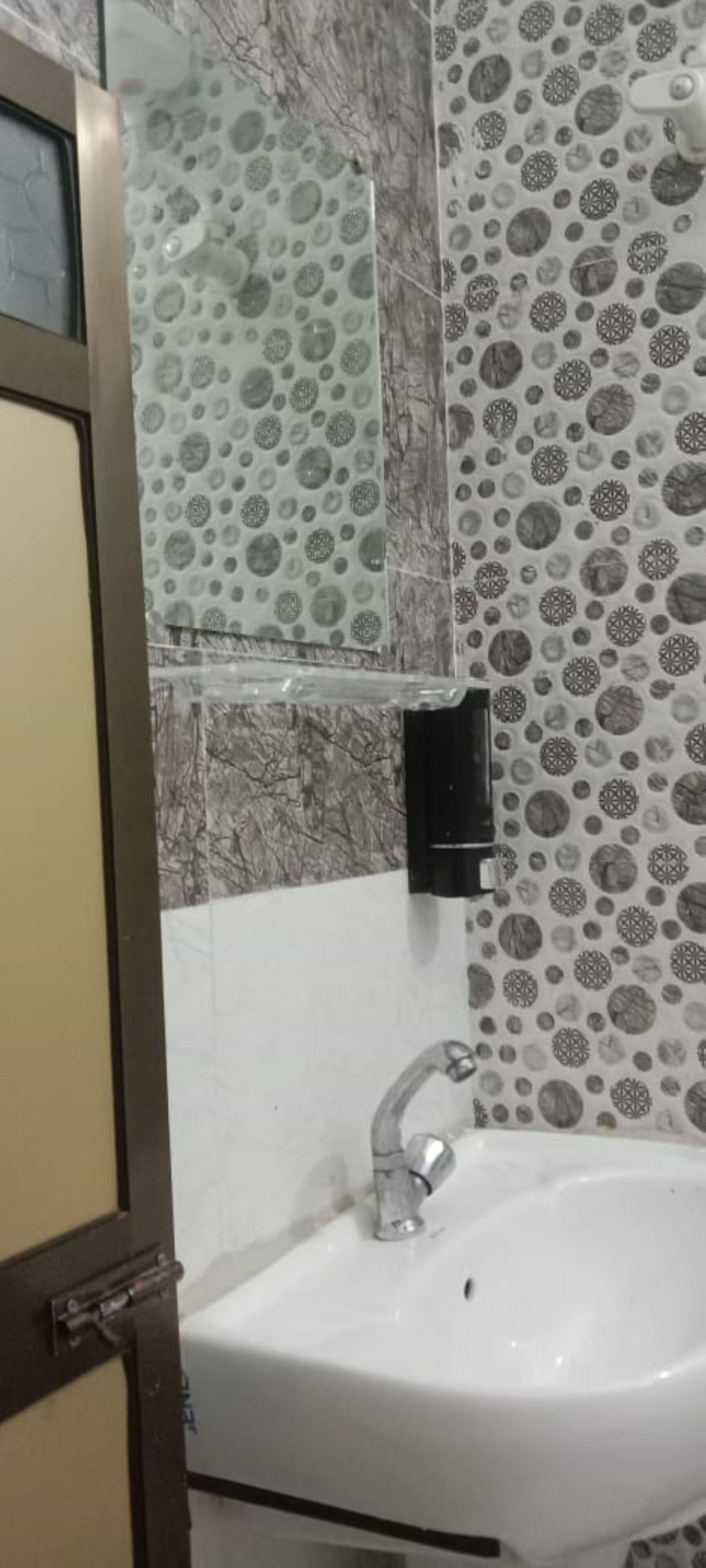 Een badkamer met een witte wastafel, een spiegel en decoratieve tegels op de muren.