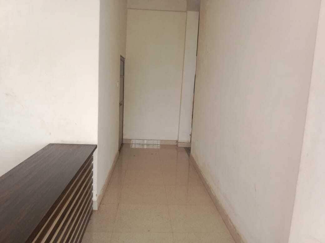 Un pasillo estrecho con un banco de madera a la izquierda y una puerta al final.