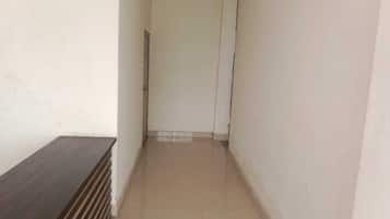 Un pasillo estrecho con un banco de madera a la izquierda y una puerta al final.