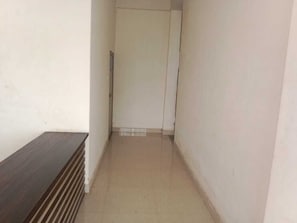Un pasillo estrecho con un banco de madera a la izquierda y una puerta al final.