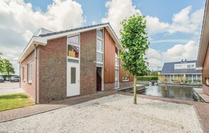Ein modernes, zweistöckiges Haus mit Backsteinfassade, großen Fenstern und einem kleinen Teich im Vordergrund.