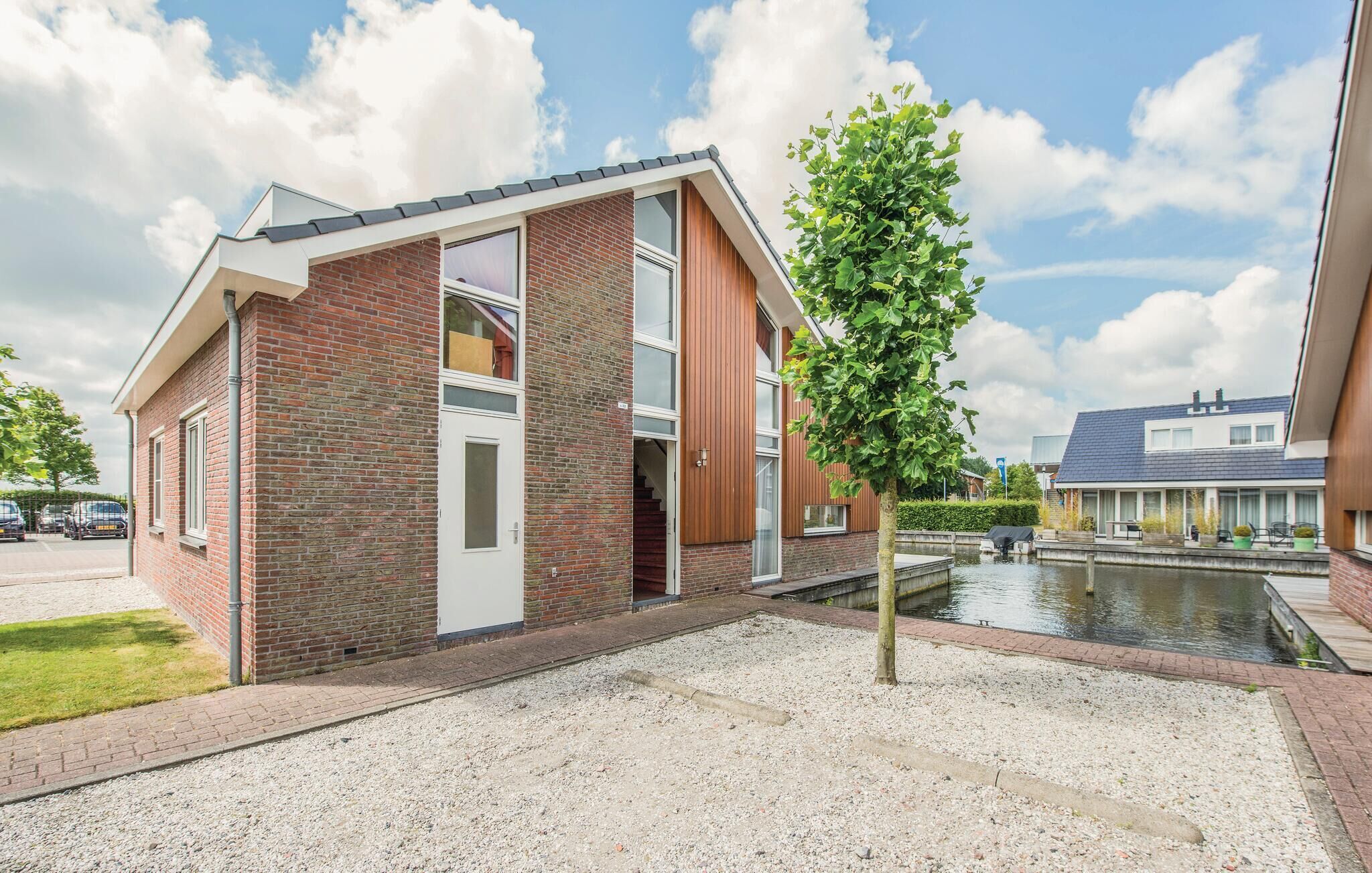 Ett modernt hus i två våningar med en fasad av tegel, stora fönster och en liten damm på framsidan.