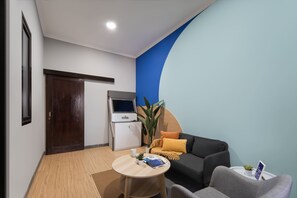 Una sala moderna con un sofá, una mesita y una zona de cocina con refrigerador.