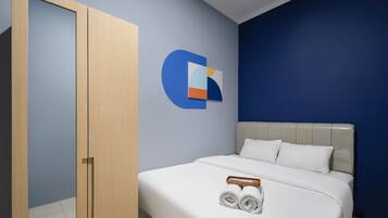 Una camera d'albergo con un letto, un armadio in legno, una parete azzurra e un logo al muro.