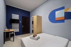 A hotel room with a bed, a desk, a chair, and a wardrobe. - Cove Stariez Auria (Jakarta)