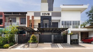 A modern building with a prominent 'Cove' sign, a gated entrance, and a red car parked in front.