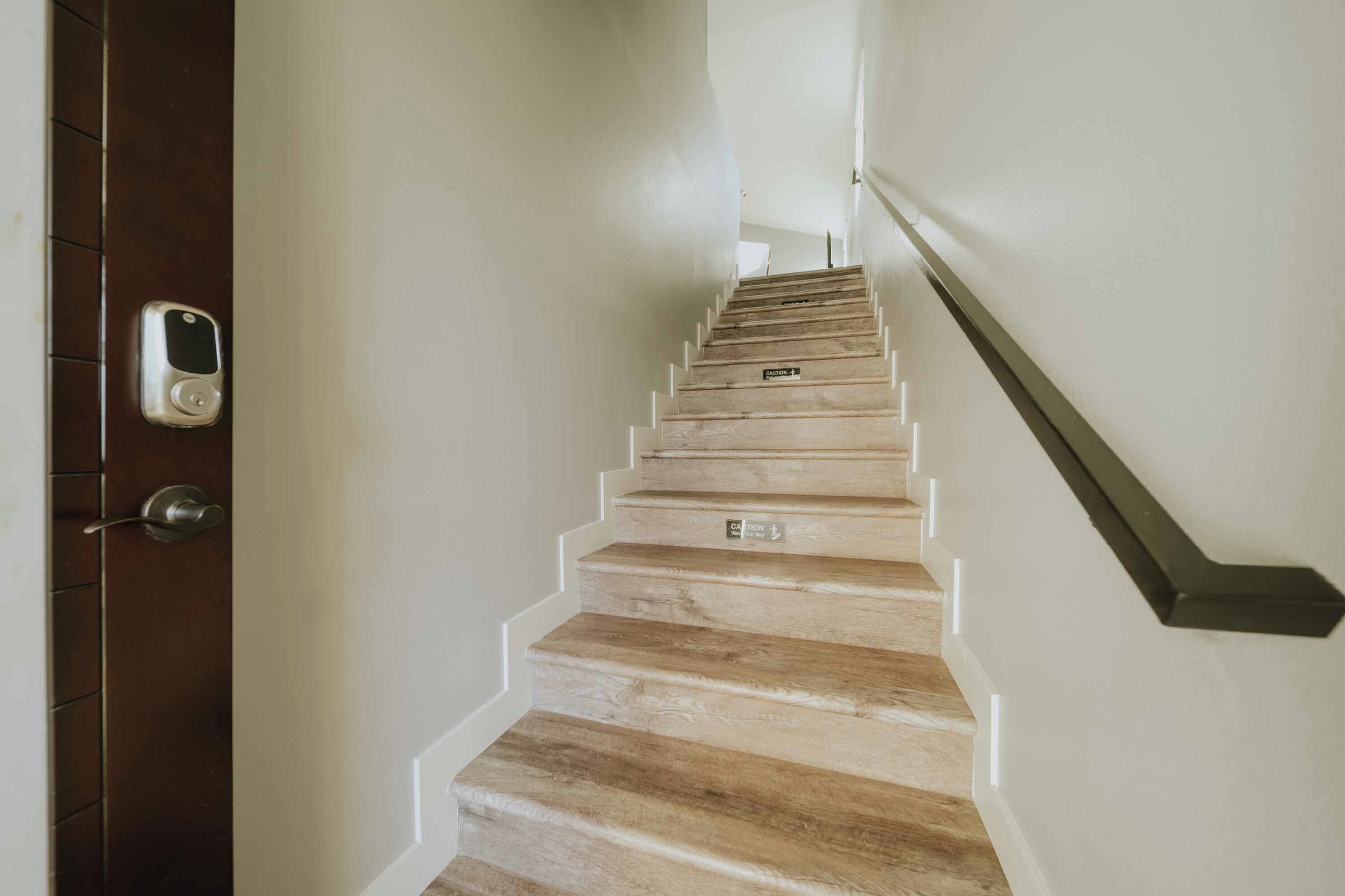 A staircase with a wooden finish and caution signs on the steps.