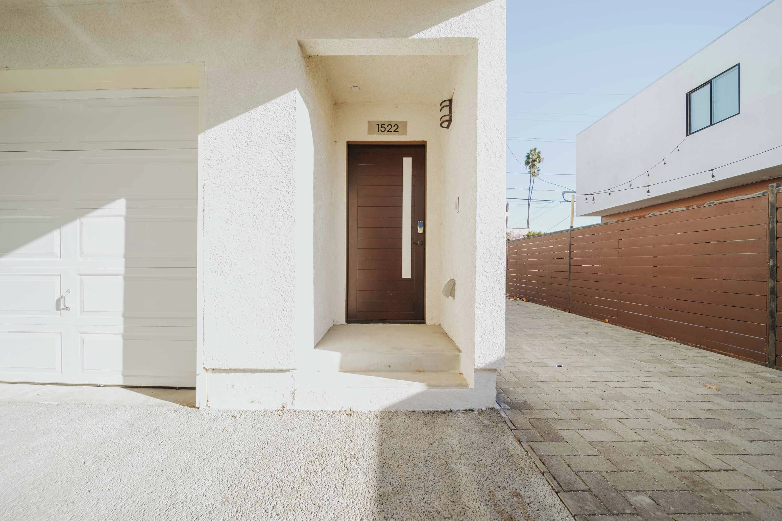 A residential entrance with a garage door, a brown door, and a mailbox.