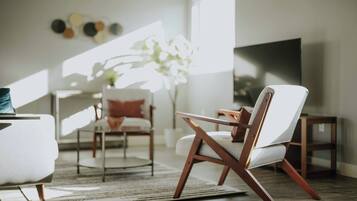 A modern living room with a sofa, a chair, a coffee table, and a TV.