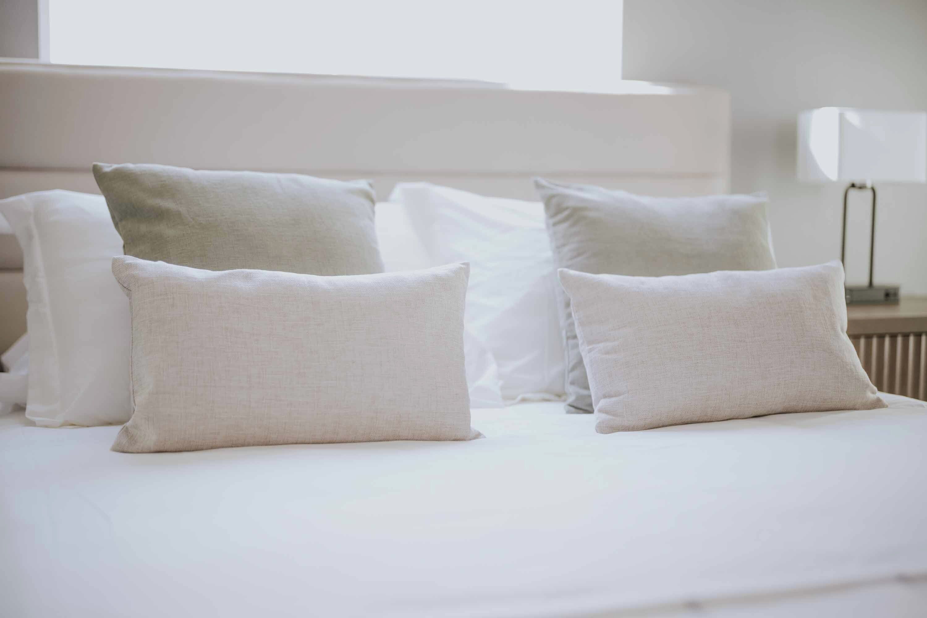 Una cama bien hecha con ropa blanca y almohadas.