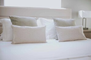 Ein ordentlich bezogenes Bett mit weißer Bettwäsche und Kissen.