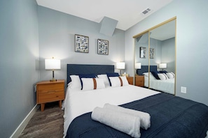 A hotel room with a large bed, two bedside tables, a mirror, and artwork on the wall. - Stylish 3BR LA Home Near Beverly Hills, LACMA & The Grove (Los Angeles)