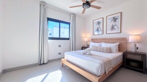 A bedroom with a bed, two bedside lamps, a ceiling fan, and two framed pictures on the wall. - Peaceful Pool View Walk to Fun Beach Dine Shop (Punta Cana)