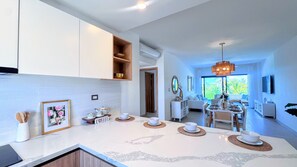 A modern kitchen with a dining area, featuring a central island with placemats, a chandelier, and a view of the outdoors. - Peaceful Pool View Walk to Fun Beach Dine Shop (Punta Cana)