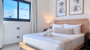 A hotel room with a bed, a nightstand, a lamp, and two framed pictures on the wall. - Peaceful Pool View Walk to Fun Beach Dine Shop (Punta Cana)
