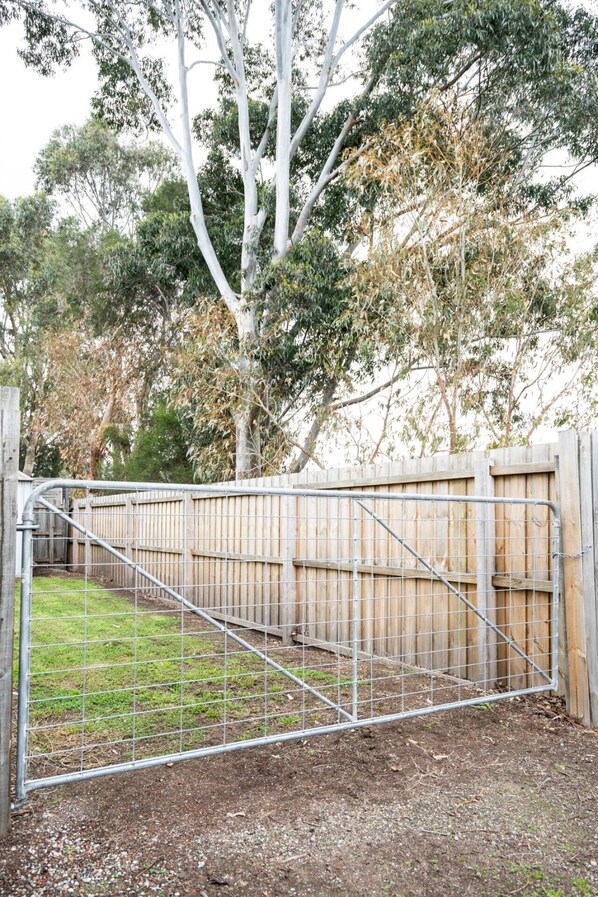 A gated area with a metal fence, wooden fence, and trees in the background.