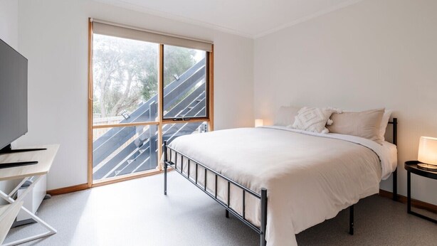 Une chambre à coucher avec un lit, un bureau et une grande fenêtre.
