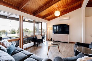 A spacious living area with a large TV, comfortable seating, and a glass coffee table.