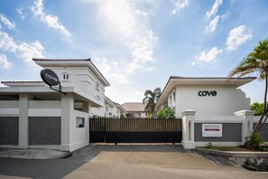 Un complejo residencial amurallado con varios edificios, cielo despejado y una palmera.