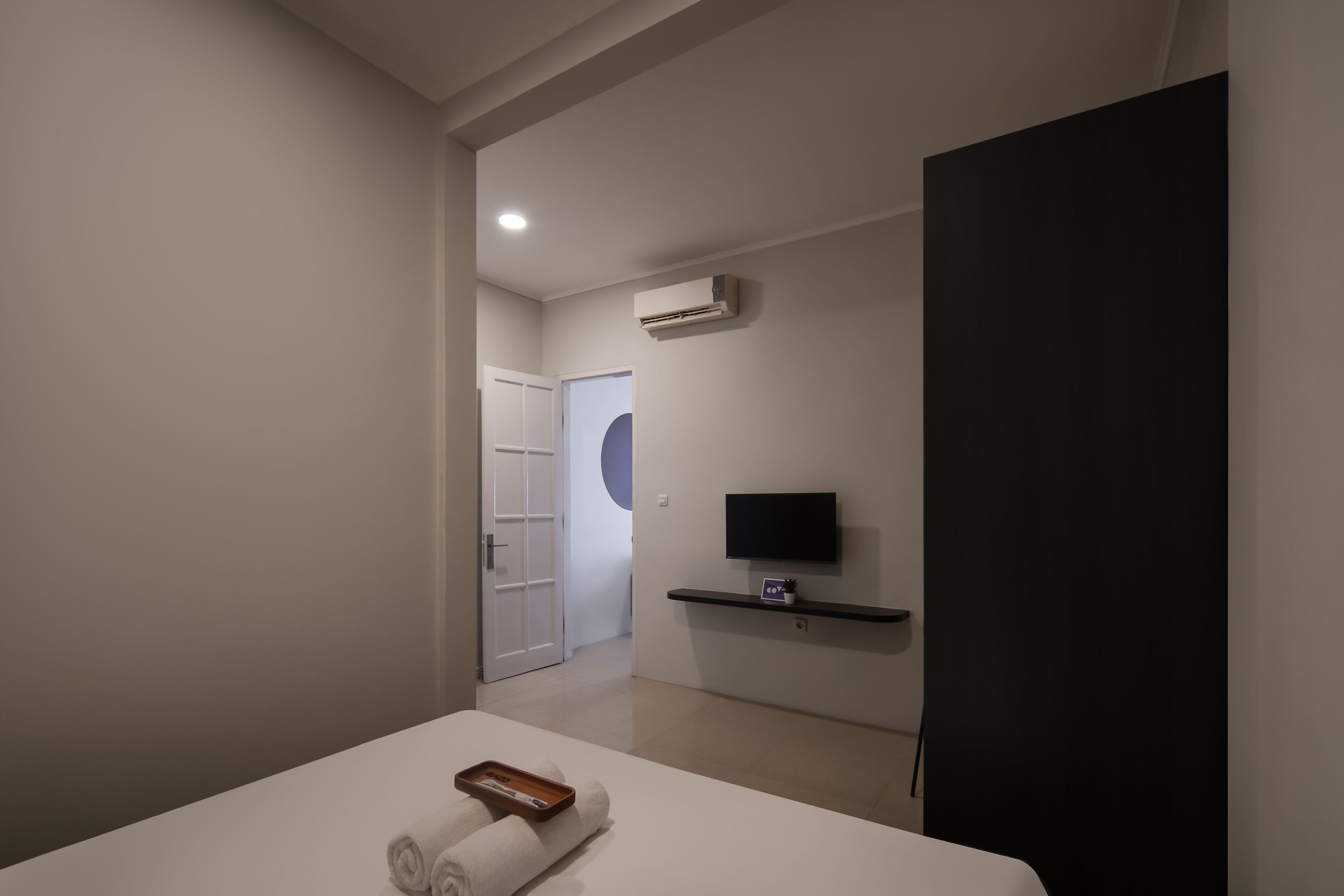 A modern hotel room with a bed, a TV, and an air conditioning unit.