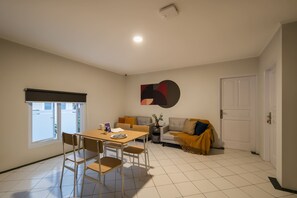 A compact living space with a dining area, a sofa, and a door.