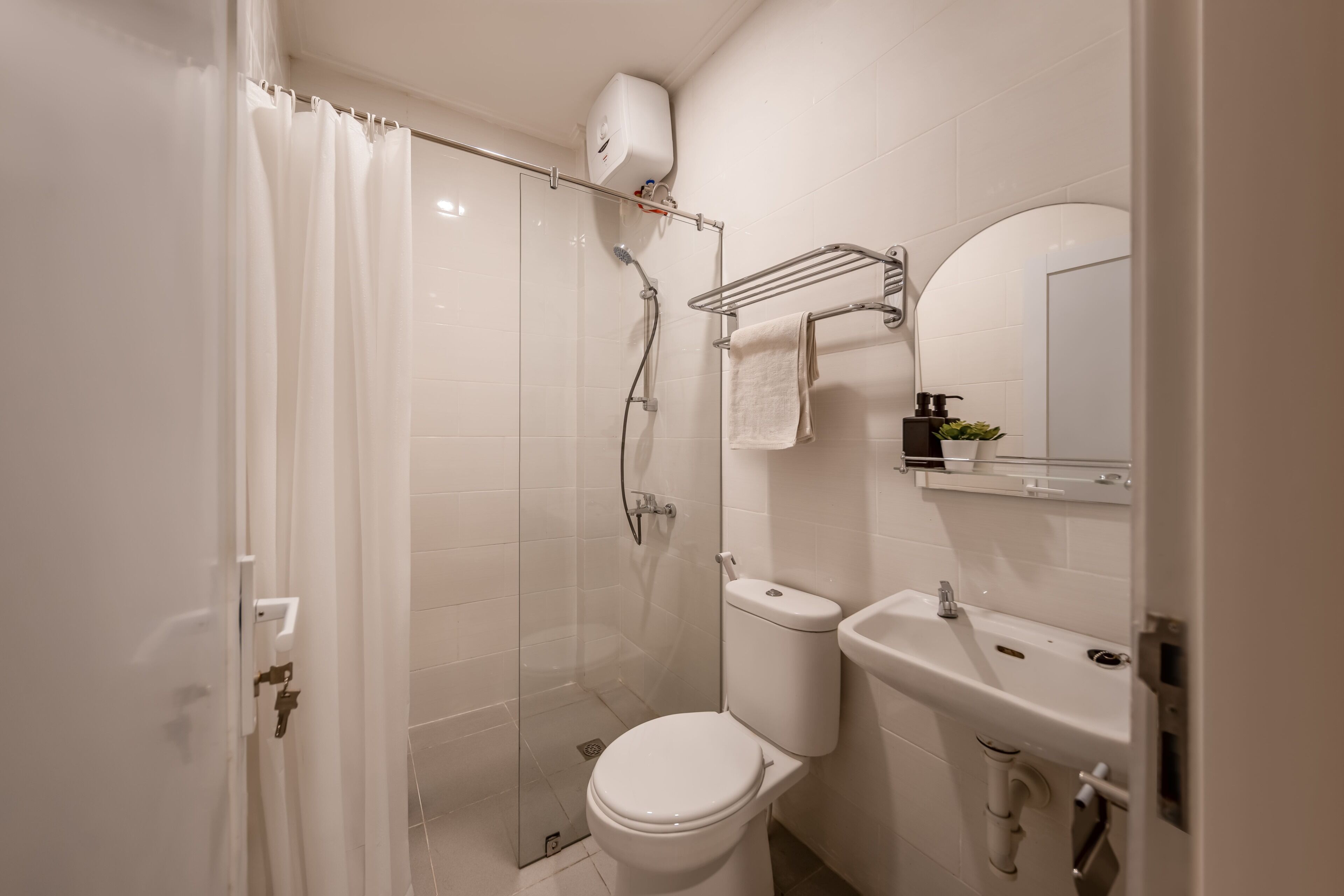Une salle de bain avec une douche à parois de verre, des toilettes, un lavabo et un porte-serviettes.