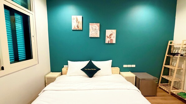 A bedroom with a teal accent wall, a bed with white bedding, and three wall-mounted artworks.