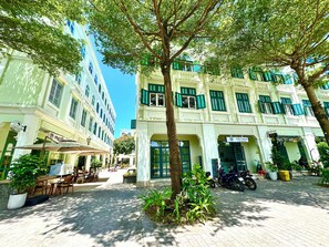 Um pátio com uma árvore, área de estar ao ar livre e um edifício com a placa 'Sweet House Hotel'.