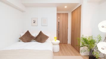 Ein modernes Schlafzimmer mit Bett, Nachttischen, einer Pflanze und einem Kleiderschrank.