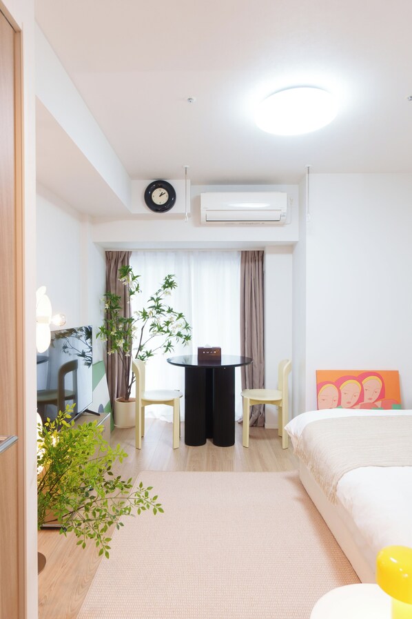 A hotel room with a bed, a desk, a chair, a potted plant, and a window with curtains. - Tora Hotel Kitashinjuku (Tokyo)