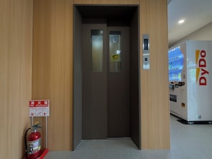 An elevator with a fire extinguisher mounted on the wall beside it.