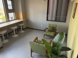 A room with a seating area, a window, a plant, and a wall-mounted cabinet.