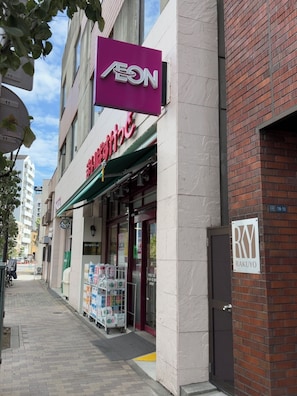A building with a purple sign labeled 'AEON' and a storefront with a green awning.