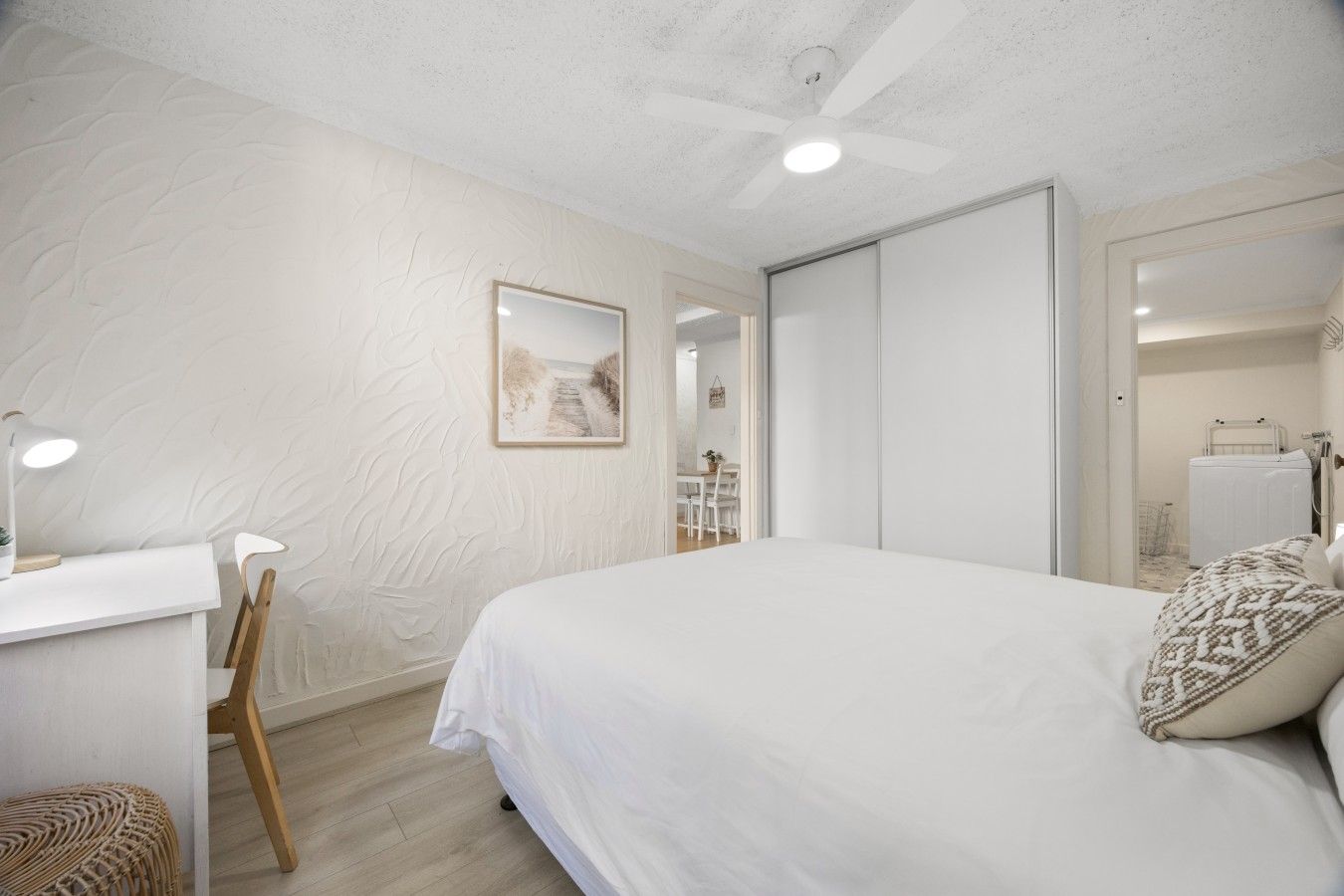 Un dormitorio con cama, escritorio, silla y ventilador de techo.