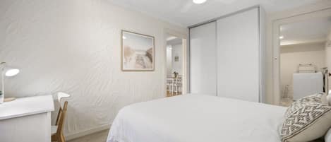 Un dormitorio con cama, escritorio, silla y ventilador de techo.