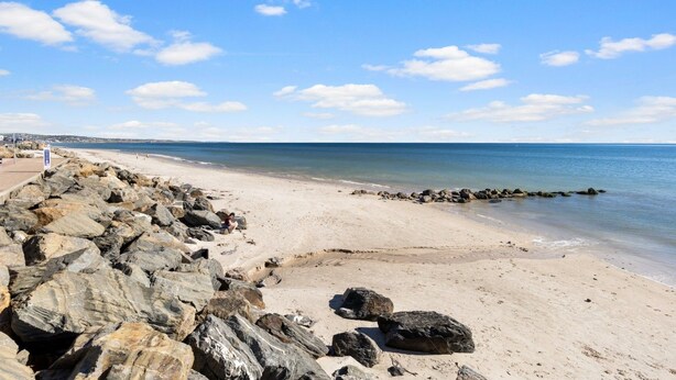 Ein Strand mit felsigem Ufer und blauem Himmel.