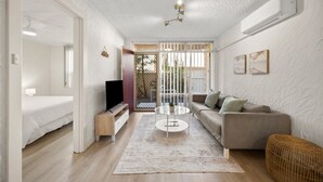 Ein modernes Wohnzimmer mit einer Couch, einem Couchtisch, einem Fernseher und einem Balkon mit Aussicht.