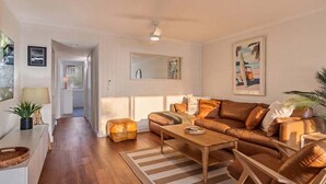 A living room with a sofa, coffee table, and chairs. There is a staircase leading to another room.