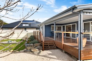 A modern house with a covered outdoor area, a gravel driveway, and a stone wall. - A Swell Time—Spacious Garden Haven by the Coast (Goolwa Beach)