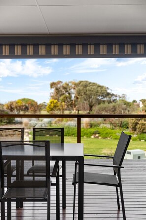 Eine Terrasse mit Tisch und Stühlen mit Blick auf einen angelegten Garten und Bäume.