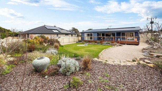 A residential property with a well-maintained lawn, a stone feature, and a modern house with a large windowed porch. - A Swell Time—Spacious Garden Haven by the Coast (Goolwa Beach)