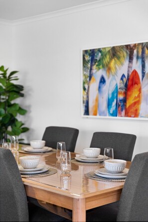 Ett matbord dukat med tallrikar, skålar och glas, omgivet av stolar.