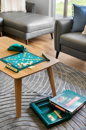 Et Scrabble-spil på et træbord med en Scrabble-æske ved siden af.