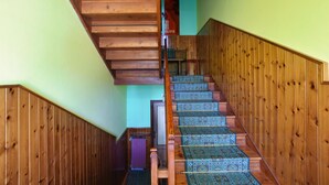 Eine Holztreppe mit gemustertem Teppich, die zu einem Raum mit grüner Wand führt.